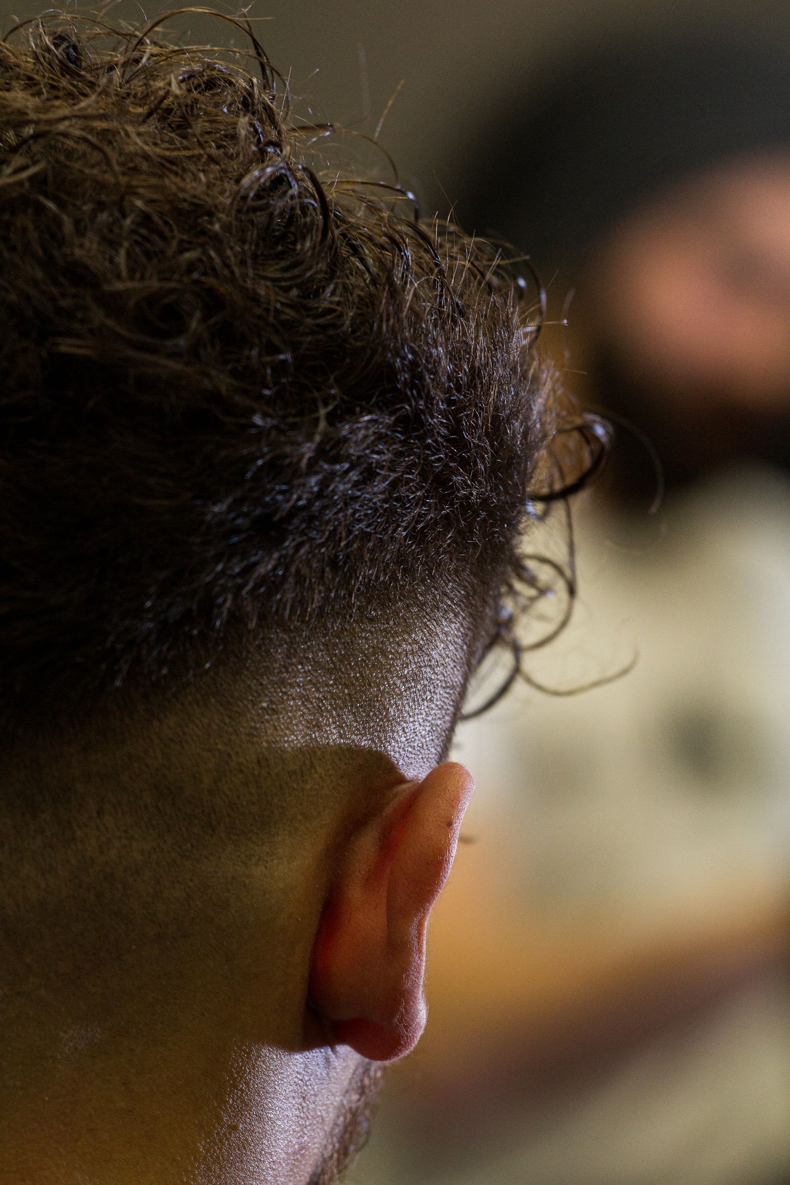 The back of a client's head with a curly top and a low fade around the ear.